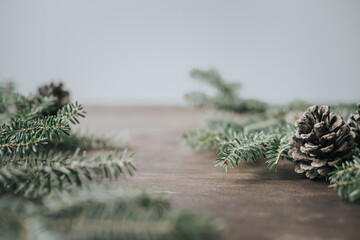 Minimalistic winter christmas background. Fir branches and cones on a wooden table.