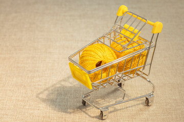 Shopping basket on wheels. Balls of yellow yarn for knitting