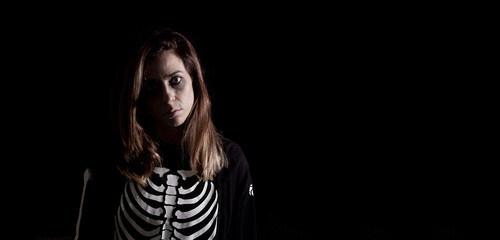 Young woman in halloween skeleton costume. Night of the dead. Copy space. Selective focus.