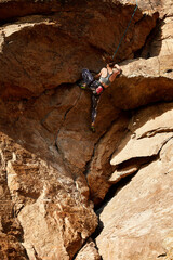 Young woman climbing at the high rock