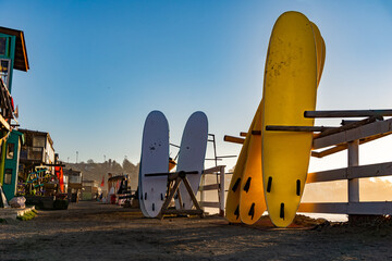 white and yellow surfboards stored in a shop on a sandy floor on the beach in concon, Chile
