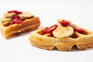 Delicious breakfast with waffles. Belgium waffle topped with boysenberry syrup, whipped cream, walnuts, banana, egg, chicken and freshly chopped strawberries horizontal shot, top view with front view