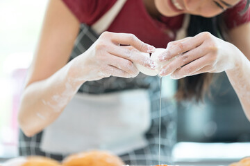 close up housewife or chef hands cracking fresh egg yolk and dropping in a bowl