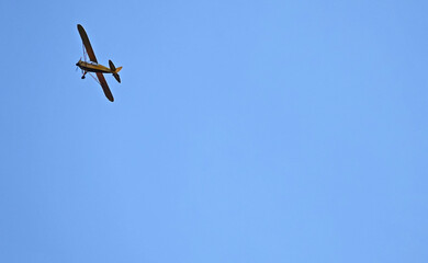 A small single-engine plane in a blue cloudless sky. With space for your own text