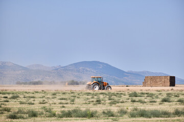 Obraz premium Tractor working in the harvest on a summer day in Castilla la Mancha