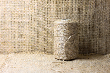 Spool of brown thread for burlap on brown burlap background with beautiful brown fabric canvas...