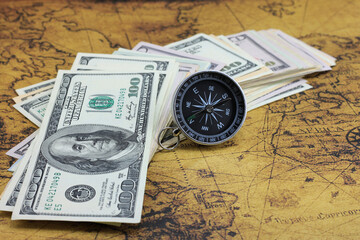 Classic navigation compass on background of old world map and american dollars as symbol of tourism with compass, travel with compass and outdoor activities with compass