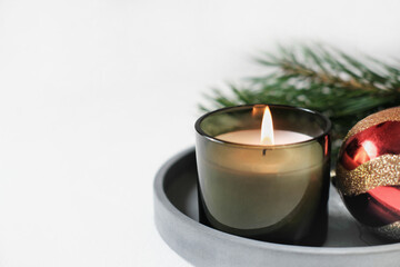 burning christmas green candle on a concrete tray next to new year decor. hcopy space, home scents for cozy atmosphere.