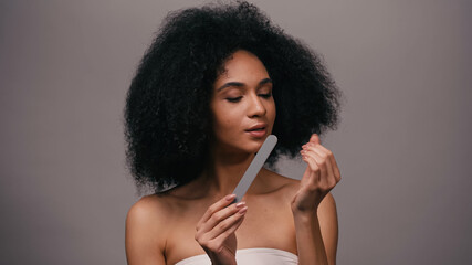 brunette african american woman using nail file isolated on grey