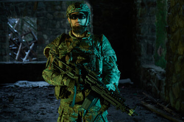 Fototapeta premium Portrait of airsoft player in professional equipment with machine gun in abandoned ruined building. Soldier with weapons at war