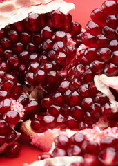 Ruby ripe fresh juicy sliced pomegranate isolated on red background