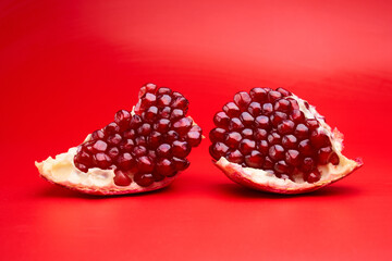 Ruby ripe fresh juicy sliced pomegranate isolated on red background