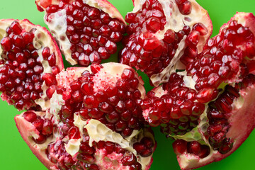 Red ripe fresh juicy sliced pomegranate isolated on green background