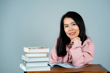 Portrait of an Asian girl wearing a pink shirt. reading a book nice back background gray studio