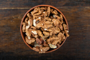 Walnut in clay bowl on wood background with copy space.