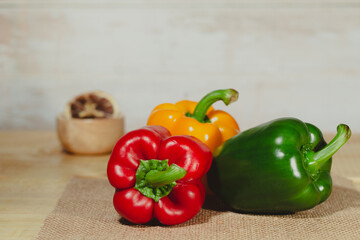 Sweet pepper, red, green, yellow paprika, on wooden background with Thai herb
