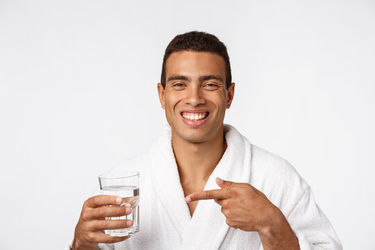 An Attractive Man Drinking A Glass Of Water Against White Background