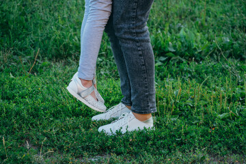 mother and daughter legs and shoes on the grass, only feet