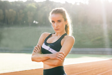 Portrait of beautiful woman in sport clothes professional athlete looking at camera after physical training. Nice girl resting outdoor after power workout and physical activity. Sports and workout