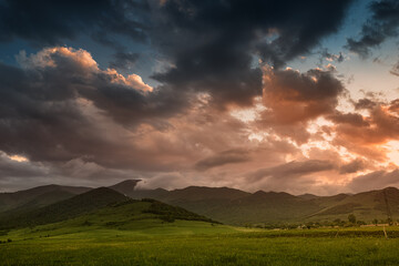 Obraz na płótnie Canvas A colorful sunset with many layers of clouds over a high mountain range as background or wallpaper