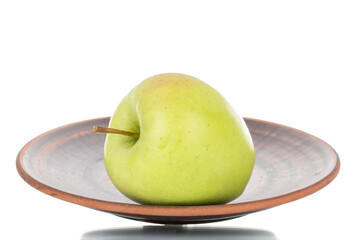 One ripe green apple on a plate of clay, close-up, isolated on white.