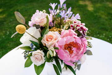 Bridal bouquet of pink peonies and pink and white roses  Light white roses and pink peony beautiful wedding bouquet of fresh flowers on the white table with green background Close up 