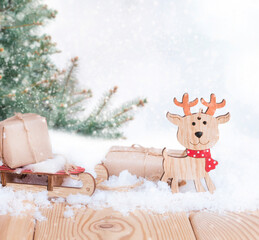 christmas presents on the wooden sled and noel toy in the snow with christmas tree in the forest