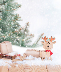 christmas presents on the wooden sled and noel toy in the snow with christmas tree in the forest with copy space
