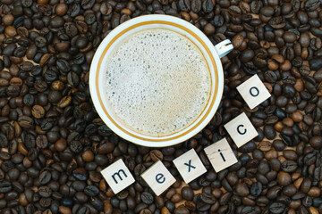 Top view of a cup of coffee on a background of coffee beans with the inscription Mexico. Country of...