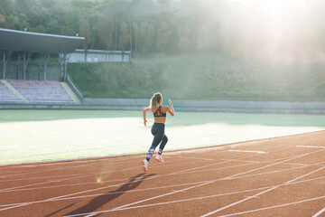 Female marathon runner on professional sports arena. Fitness woman racing at stadium. Female sprinter race on outdoor track arena. Motivated girl winning speed contest