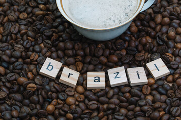 Top view of a cup of coffee on a background of coffee beans with the inscription Brazil. Country of...
