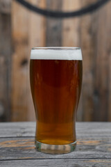 Brew. Closeup view of an amber ale with perfect foam in a glass on the wooden table.
