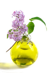Close-up of a lilac essential oil with a lilac flower on a white background.