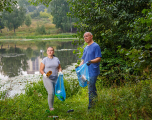 A woman and a man volunteers clean up garbage from a landfill in the park.