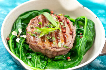 Sirloin steak with spinachd served in a pan.