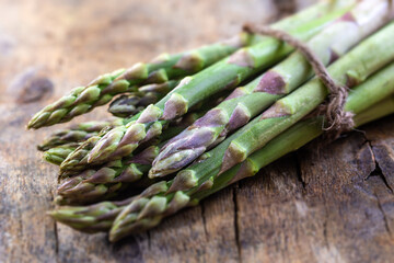 Green fresh asparagus on old wooden background.