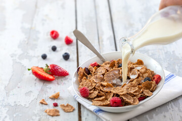 Healthy cereal breakfast. with Berries - fresh strwberries and blueberries, with milk pourring.