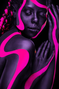 Neon colors. Pink and black body paint. Woman with face art. Young girl with colorful bodypaint. An amazing afro american model with makeup.