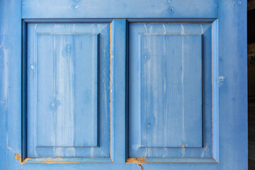Entrance wooden closed door with blue shutters details close-up. Greek traditional house design elements. Summer travel locations architecture house elements