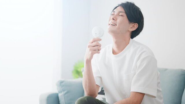 ハンディ扇風機で涼しんでいる男性