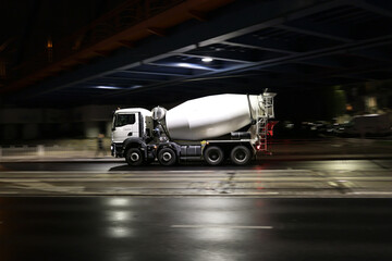 Duży samochód ciężarowy betoniarka w drodze na budowę nocą w mieście.  - obrazy, fototapety, plakaty