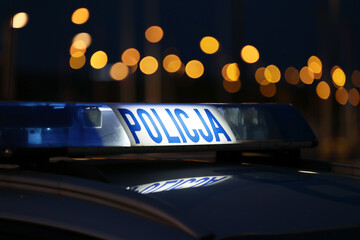Sygnalizator błyskowy niebieski na dachu radiowozu policji polskiej w nocy. 