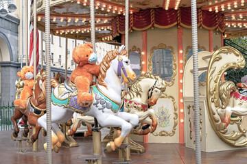 Fototapeta na wymiar Teddy bear in a medical mask rides on a children's circular carousel.