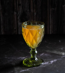 Natural, apple juice in a green wine glass on a dark background.
