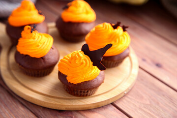 Halloween chocolate cupcakes with decor on wooden background
