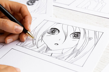 The artist draws anime comics on paper. Storyboard for the cartoon. The illustrator creates...