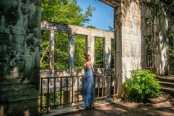 Fototapeta na wymiar Beautiful redheaded woman in front of the stone ruins of the Willson Carbide Mill in Gatineau Park near Ottawa, Canada.