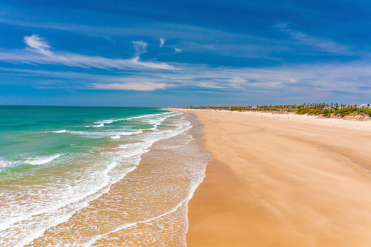 Aerial view of the beach of Playa La Ballena with a long sandy shoreline and turquoise waters in Cadiz, Andalusia, Spain.