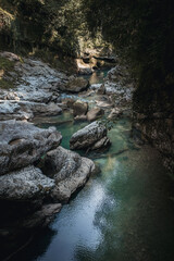 A gorge in a canyon with a clean cold mountain river - a fast current in the mountains among stones and sheer cliffs