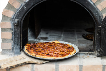 Pizza made in a white painted artisan wood oven built on the outside